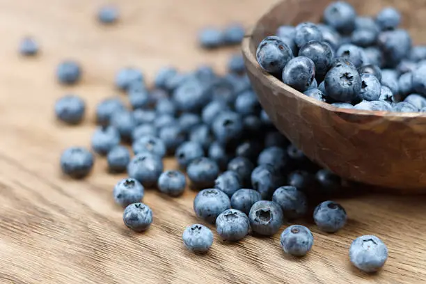 Freshly picked blueberries in bowl on wooden background. Shallow depth of field