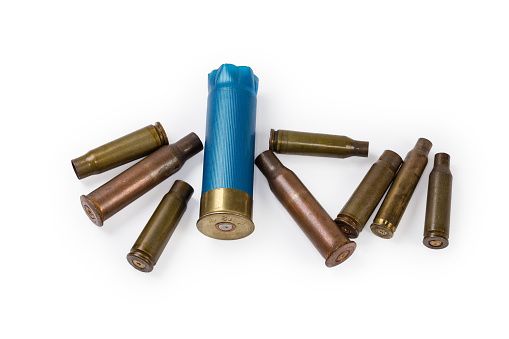 Spent shotgun shell 12 gauge with brass base and blue plastic hull and spent shells different calibers from assault rifles on a white background