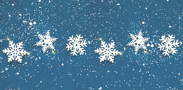 Winter pattern made of snowflakes on knitted texture  in blue metallic colors. Christmas decor or hygge style. Creative copy space. Close-up