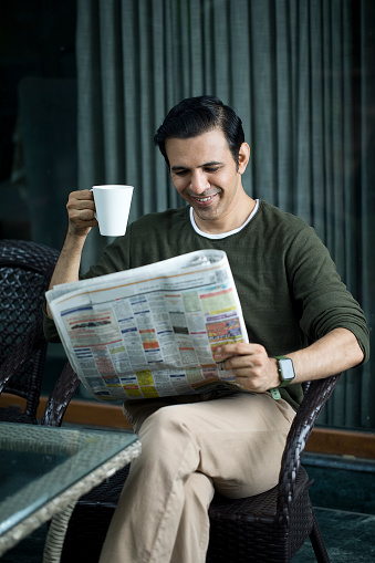 Mid Adult Man Reading A Newspaper And Drinking Coffee At Home