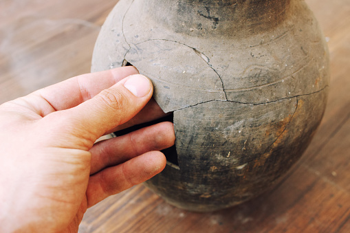Man hand restoration broken fragments earthenware jug