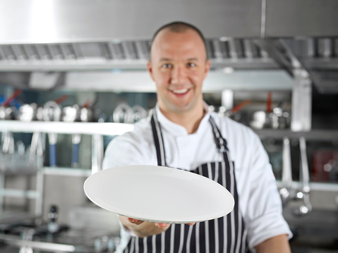 Chef holding an empty plate in a commercial kitchen
