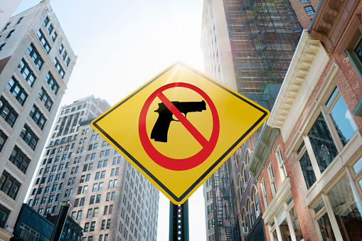 Road sign quoting “Stop gun violence” in an urban background