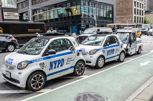 Small police cars parked on New York street during summer day.