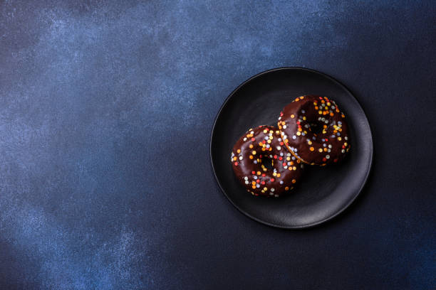 istock Pastries concept. Donuts with chocolate glaze with sprinkles, on a dark concrete table 1419915162