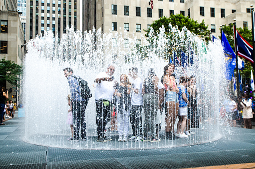 People surrounded by water fountain in Manhattan during summer day