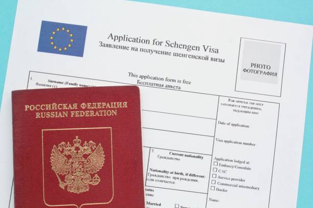 istock Schengen visa application form in English and Russian language and passport on blue background 1419916052