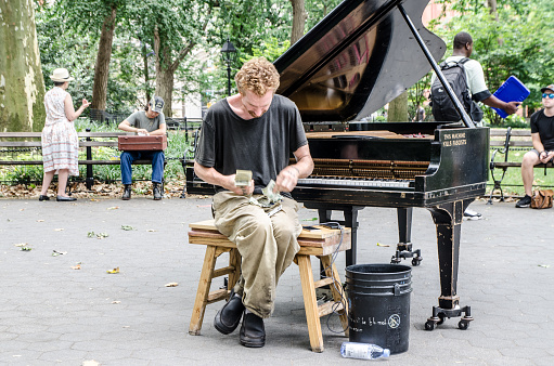 Street performer counting his money after playing piano on the Street in New York city during summer day