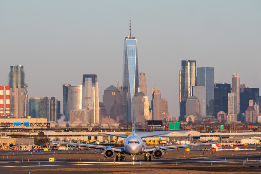 Airplane have just landed in airport Newark. Passenger plan on runway strip to go to Terminal of airport. New York city on background of airplane