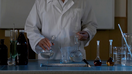 Measuring glass with smoke on a table of a chemical laboratory. Glass flask with chemicals and dry ice on a dark background