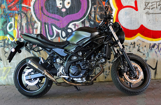 Rheine, NRW, Germany - August 24 2022 A black Suzuki SV650 motorcycle standing in front of a graffiti wall