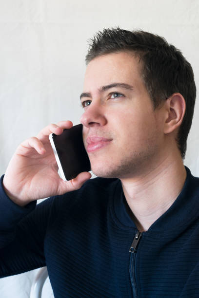 istock Attractive young man talking on the phone with a white wall background 1419922911