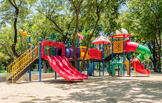 Five elementary-age children play during school recess or at a park setting. Playground equipment, slide. 