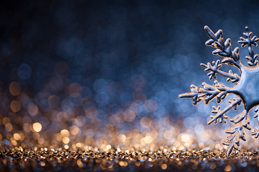 Huge ice crystal on defocused gold and blue lights. Decorative Christmas still life photography. Native image size: 5616x3744
