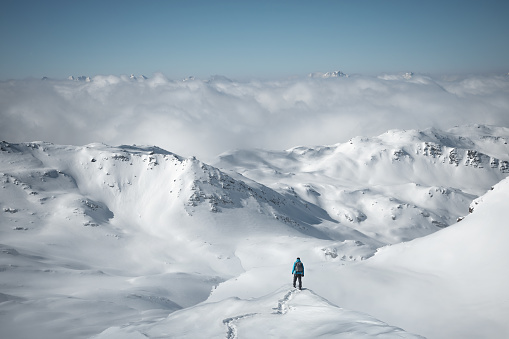 Man standing on the edge of the snowcapped mountain and enjoying the view.