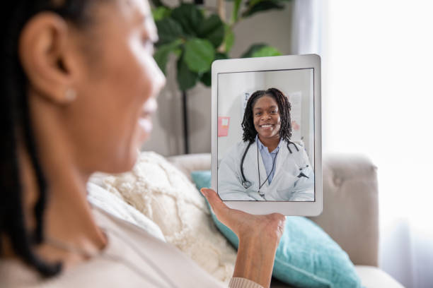 Mature woman discusses health issue with doctor during a telehealth appointment stock photo