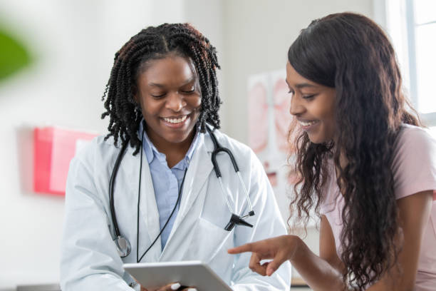 Young female patient discussing healthcare options with doctor at women's health clinic stock photo