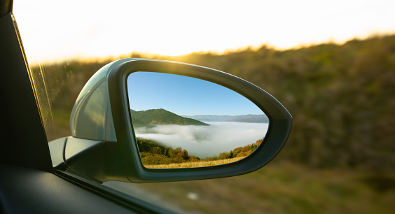 The view of the mountains in the car's rearview mirror. Travel by personal car, concept.