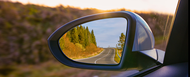 The view of the mountains in the car's rearview mirror. Travel by personal car, concept.