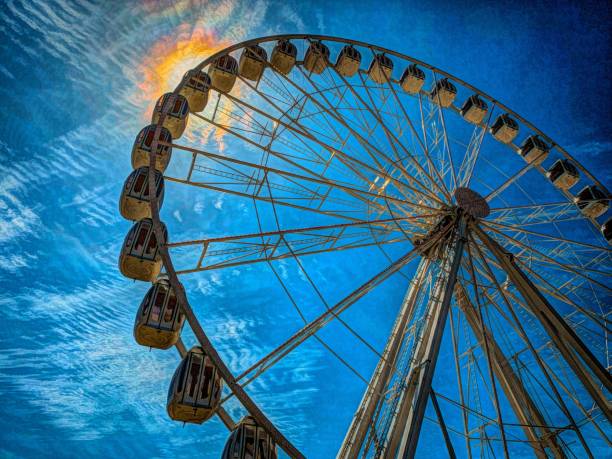 Observation wheel against sun and blue sky