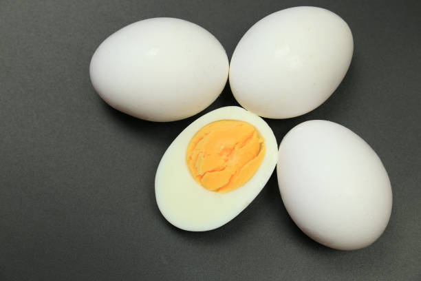 istock White eggs one of them boiled on black background 1419936836