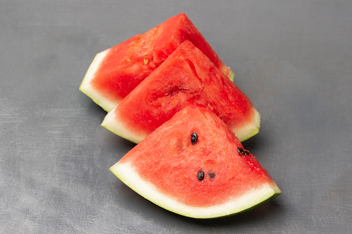 Three pieces of watermelon, part of the frame. Copy space. Top view. Grey background.