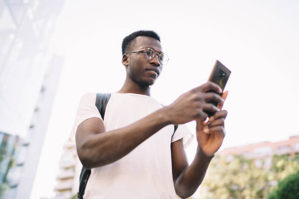 mensagem de texto do homem focado no telefone na rua - young men looking up thinking looking - fotografias e filmes do acervo