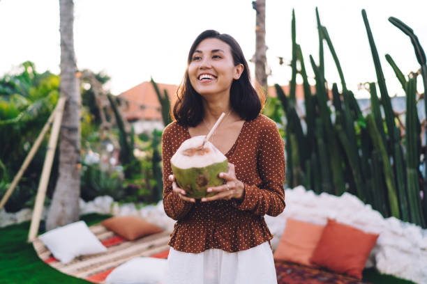 istock Cheerful young lady with coconut drink on summer terrace 1419942654
