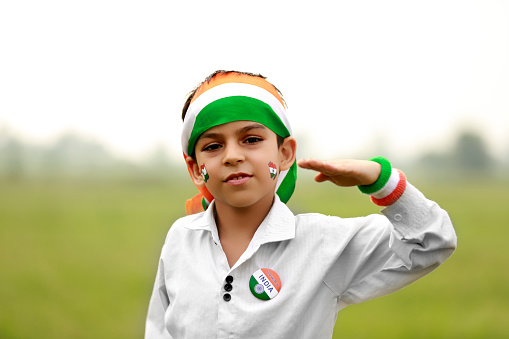 Cute elementary age child of Indian ethnicity standing portrait outdoor in nature during Independence/ Republic day celebration event.