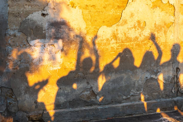 istock Shadows of dancing people on an old stone wall at sunset time. 1419950505