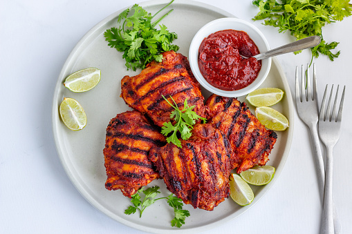 Grilled Chicken Thighs with Condiments Garnished with Cilantro and Lemon Top Down Food Photography