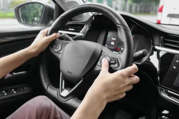 Photo of woman pressing buttons on multifunction steering wheel in car