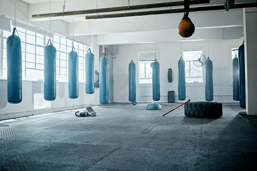 Empty boxing, health and fitness gym with workout, training and exercise equipment. A fight club, wellness or sports room full of punching bags for industry professional athlete, expert or trainer