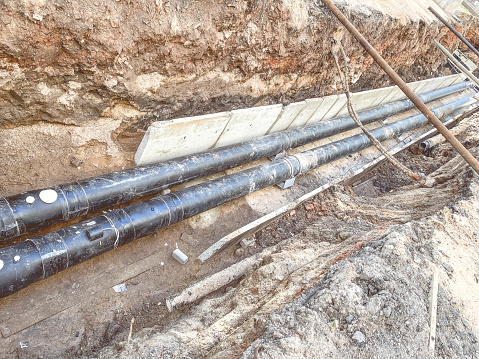 laying of underground communications for residential buildings. black plumbing pipes made of durable and reliable material lie on the foundation for digging into the ground.