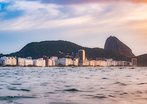Sunrise in from inside the sea in Copacabana beach,  the buildings and sugarloaf mountain in the  background, colorful sky