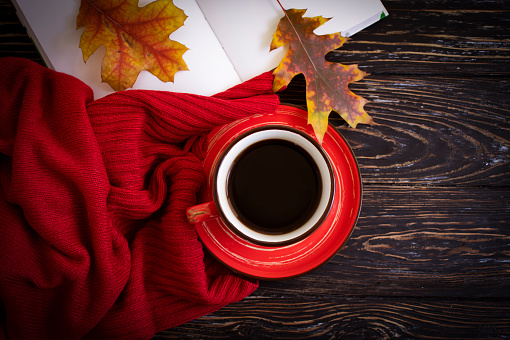 Cup of coffee, autumn leaves on old background, sweater
