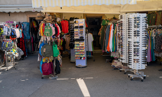 Traditional kiosks near coast on street with lot of \ntextile, glasses, swimming gear, suit, backpacks, hats, clothes valets and everything you need for vacation on coast. It is in Fazana, Istria in Croatia.