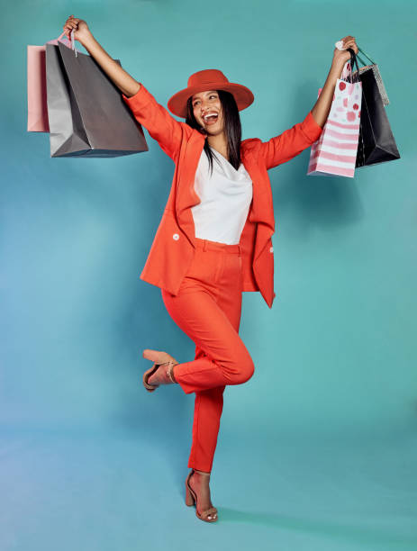 Excited and trendy woman with shopping bags after retail therapy, spending and buying clothes. Stylish, edgy and funky model holding gifts and wearing colorful, fashionable red suit while happy Fun, happy and trendy woman with shopping bags after retail therapy, spending and buying clothes. Stylish, edgy and funky model holding gifts and wearing colorful, fashionable red suit while excited shopaholic stock pictures, royalty-free photos & images