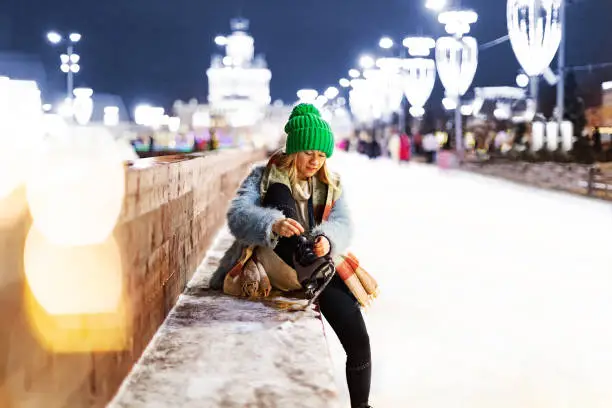 Young woman tying ice skating shoelace