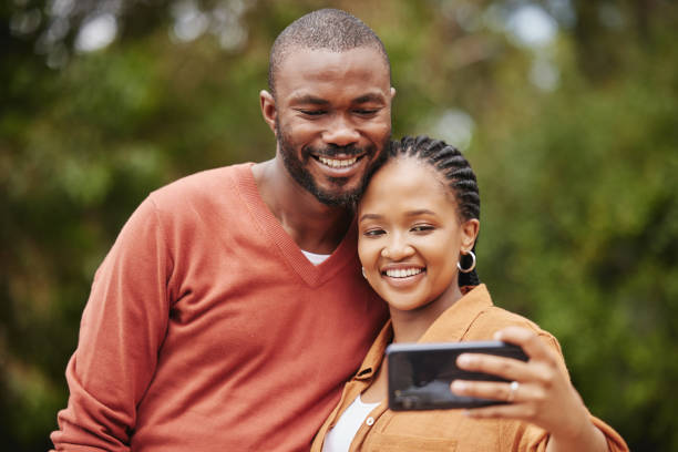 istock Trendy, modern couple taking selfie on phone while on a romantic date in a park and sharing relationship status on social media app. Smiling, in love married husband and wife capturing happy memories 1419984453