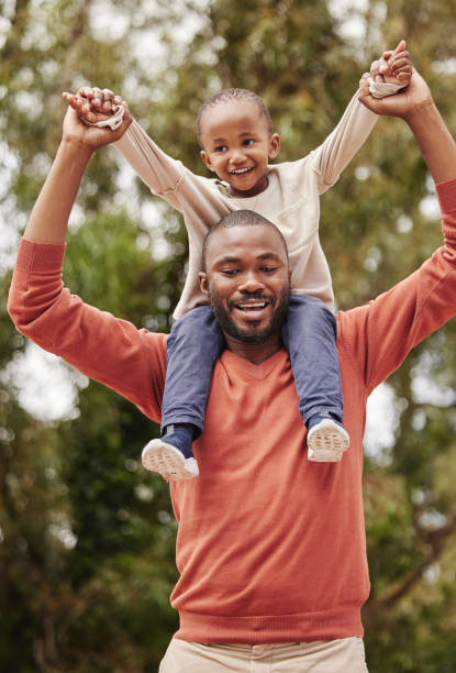 istock A young black father playing with his daughter happy, smiling and bonding while enjoying quality time together. A little girl, child or kid having fun and sitting on her dad or parent's shoulders 1419987914