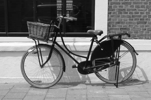 an old black bicycle parked on a wall with a window