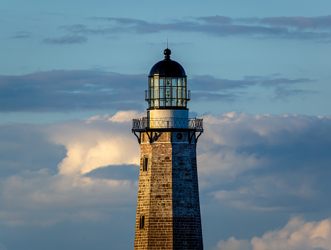 Closeup composition of Montauk Lighthouse tower in evening light backed by scattered clouds.  Montauk, Montauk Point State Park, Long Island, New York.