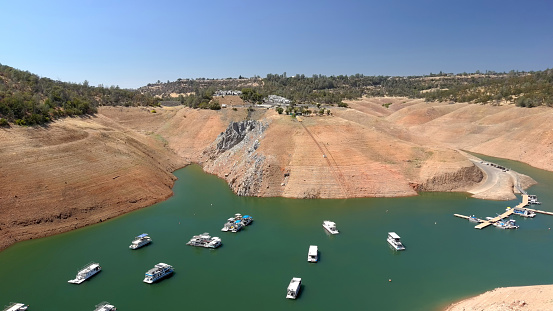 Lake Oroville during California's extreme drought. Water levels are the lowest in years. Stranded houseboats and the marina are shown against the background of the normal water level.