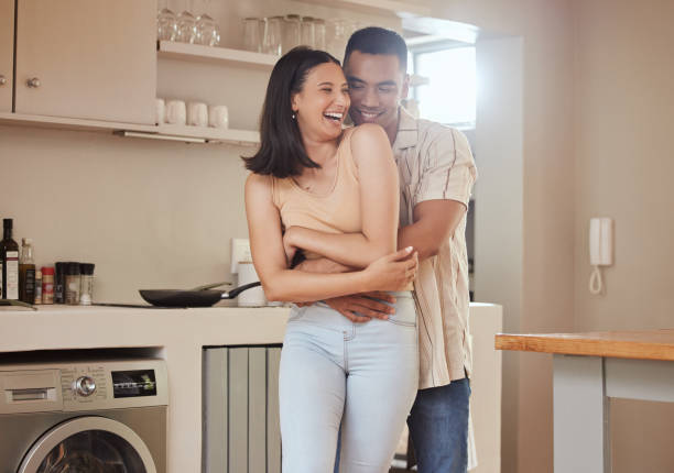 istock Happy, romantic and in love couple smiling, hugging and embracing while relaxing together indoors at home. Young, loving and sweet husband hugging his carefree, laughing and fun wife in the kitchen 1419991155