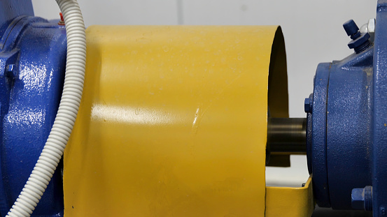 Close up of rotating element of the engine colored in blue and yellow. Metal working and production at the industrial plant, concept of heavy industry.