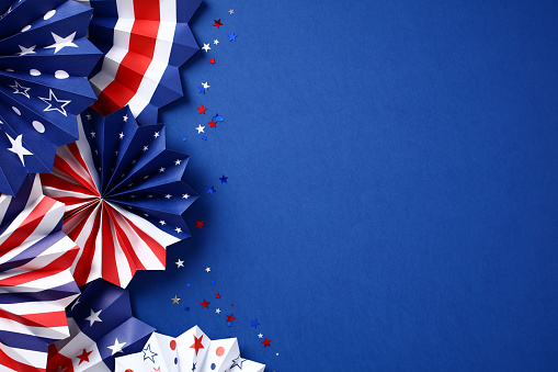 Paper fans in color of American flag and confetti on dark blue background. USA Labor Day, Independence Day, Columbus Day banner design.