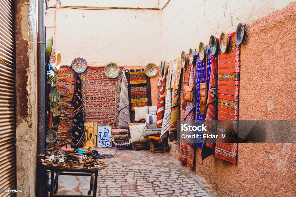 moroccan street with carpet weaving Moroccan street with carpet weavings and handicraft objects for sale. Rug Stock Photo