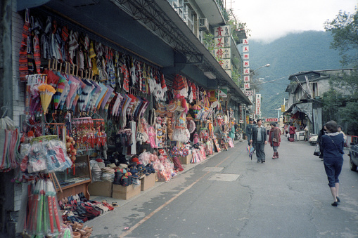 British Hong Kong, China - 1983: A vintage 1980's Fujifilm negative film scan of an open market in rural China, with items for sale hanging in display.