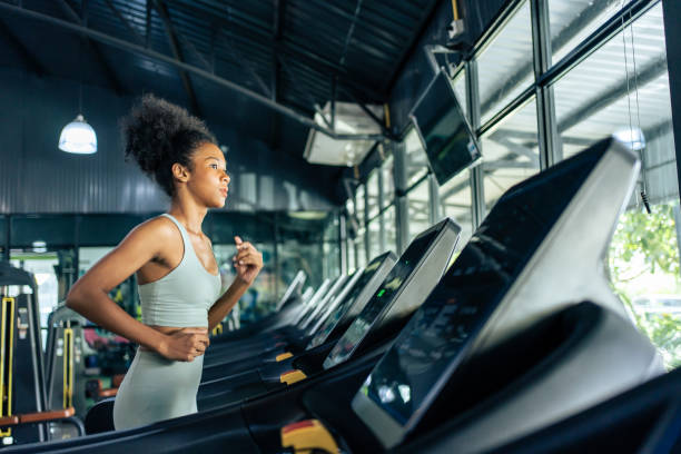 jovens esportistas afro-americanas se exercitam correndo na esteira na academia. . garota atleta bonita atraente pratica treino para manter músculo e queimar calorias para o bem-estar da saúde no estádio fitness - cardio exercise - fotografias e filmes do acervo